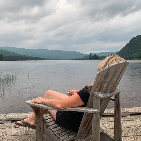 Une femme assise sur une chaise sur un quai, contemplant un lac paisible.