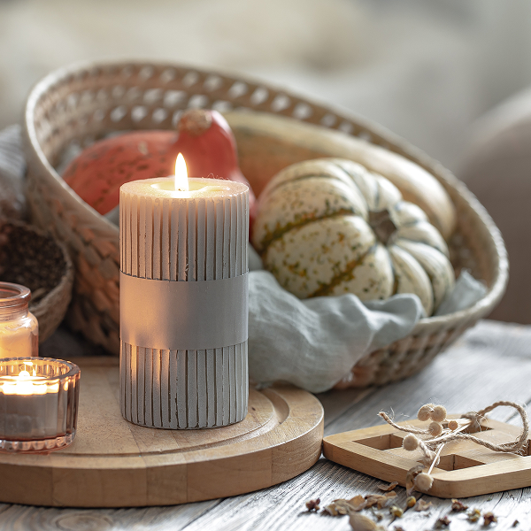 Une bougie, un panier et un panier de citrouilles, évoquant une ambiance chaleureuse et automnale.