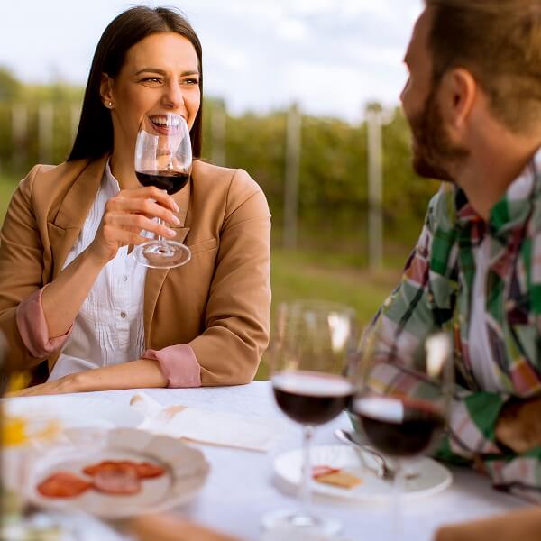 Un homme et une femme partagent un verre de vin à une table, souriant et profitant de leur moment ensemble