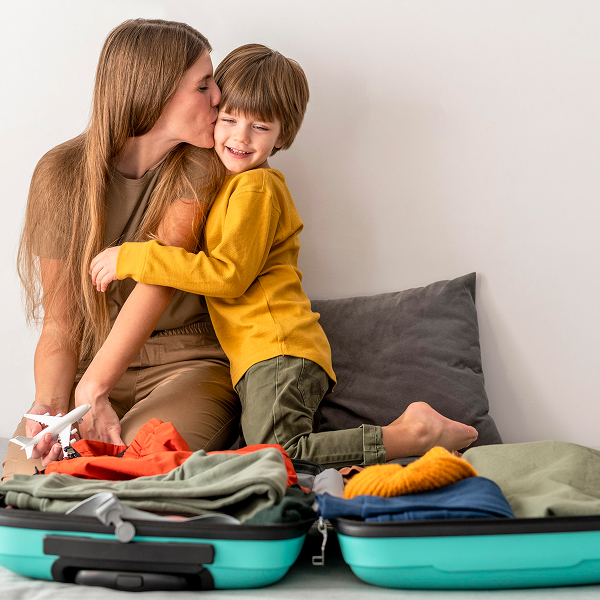 Une femme et un enfant assis sur des valises, prêts pour des vacances.
