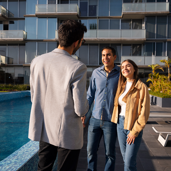 A man and two women stand by a pool, showcasing a vibrant setting for condos available for rent.