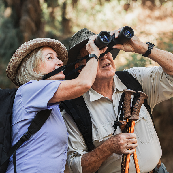 Un couple âgé observe à travers des jumelles lors d'une randonnée pédestre en pleine nature.