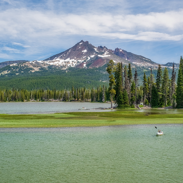 A serene lake with Mont-Orford mountain rising majestically in the background, surrounded by lush greenery.