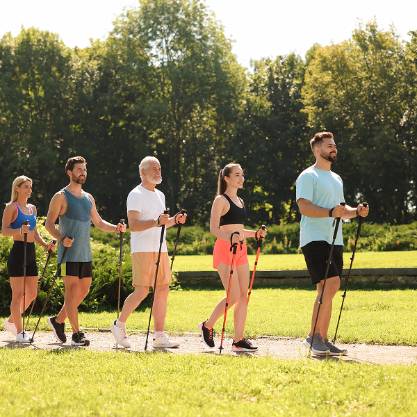 A family group walking along a path, using ski poles for support during their outdoor activity.