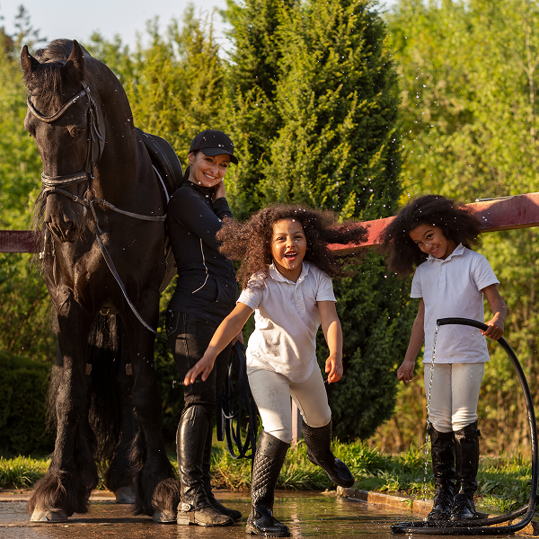 A woman and two children stand beside a horse, preparing for a horseback riding experience.