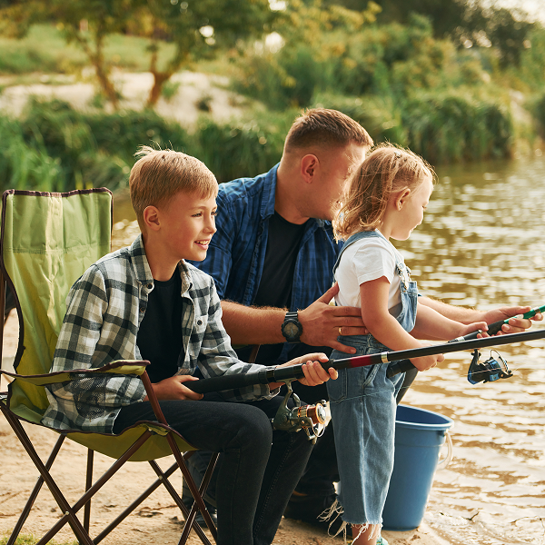 A man and two children fishing together on a serene lake, surrounded by trees and calm waters.